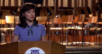 Movie still from “Disturbing Behavior” (1998), directed by David Nutter – A woman standing at a podium in front of a microphone; Medium shot, High angle