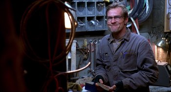 Movie still from “Disturbing Behavior” (1998), directed by David Nutter – A man sitting at a table in front of a lamp; Medium shot, Low angle