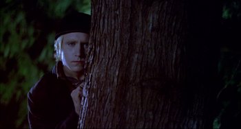Movie still from “Disturbing Behavior” (1998), directed by David Nutter – A man standing next to a tree in the dark; Medium shot, Low angle