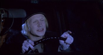Movie still from “Disturbing Behavior” (1998), directed by David Nutter – A man in a hat is holding the steering wheel of a car; Close Up shot, High angle