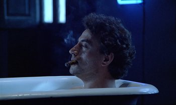 Movie still from “Diva” (1981), directed by Jean-Jacques Beineix – A man sitting in a bath tub with a cigar in his mouth; Medium shot, Low angle