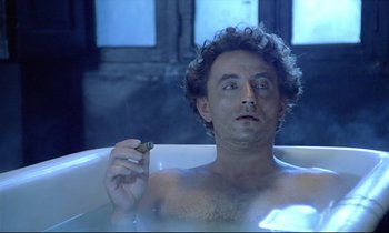 Movie still from “Diva” (1981), directed by Jean-Jacques Beineix – A man sitting in a bath tub holding a cigarette; Close Up shot, Low angle