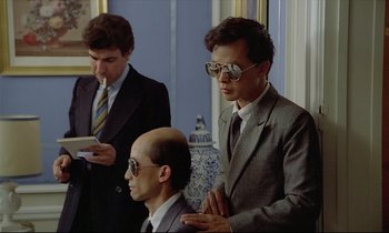 Movie still from “Diva” (1981), directed by Jean-Jacques Beineix – A man in a suit and tie standing next to another man in a suit and tie; Medium shot, Over the shoulder angle