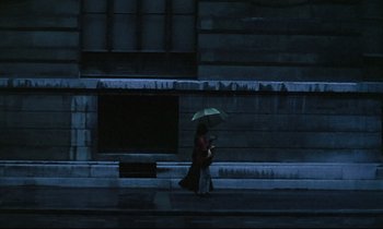 Movie still from “Diva” (1981), directed by Jean-Jacques Beineix – A woman walking down the street holding an umbrella; Extreme Wide shot, Low angle