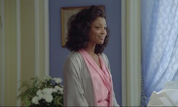 Movie still from “Diva” (1981), directed by Jean-Jacques Beineix – A woman in a pink and gray robe standing in front of a blue wall; Medium shot, Over the shoulder angle