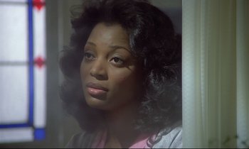 Movie still from “Diva” (1981), directed by Jean-Jacques Beineix – A black woman with long curly hair looking out of a window; Close Up shot, Low angle