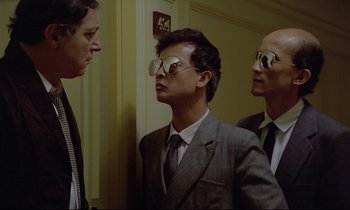 Movie still from “Diva” (1981), directed by Jean-Jacques Beineix – A man in a suit and tie standing next to two other men; Medium shot, Low angle