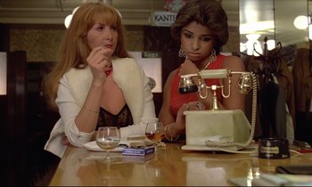 Movie still from “Diva” (1981), directed by Jean-Jacques Beineix – Two women sitting at a table in front of a phone; Medium shot, High angle