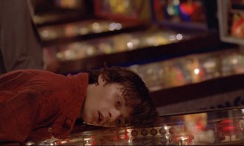 Movie still from “Diva” (1981), directed by Jean-Jacques Beineix – A young boy in a red shirt is playing a video game; Close Up shot, Low angle