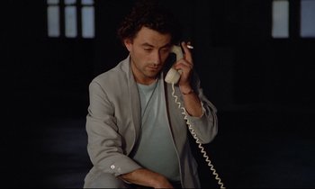 Movie still from “Diva” (1981), directed by Jean-Jacques Beineix – A man holding a phone up to his ear while sitting down; Close Up shot, Low angle