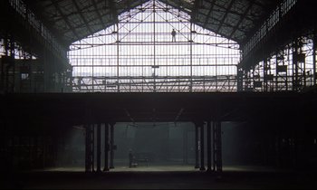 Movie still from “Diva” (1981), directed by Jean-Jacques Beineix – A large building with a person standing on top of it; Extreme Wide shot, Low angle
