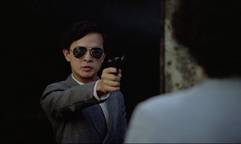 Movie still from “Diva” (1981), directed by Jean-Jacques Beineix – A man holding a gun in front of a mirror; Close Up shot, Over the shoulder angle