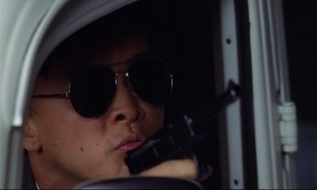 Movie still from “Diva” (1981), directed by Jean-Jacques Beineix – A man wearing sunglasses and holding a gun in a vehicle; Close Up shot, Low angle