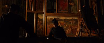 Movie still from “The Monuments Men” (2014), directed by George Clooney – A man sitting in front of a wall with paintings on it; Extreme Wide shot, Low angle