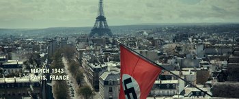 Movie still from “The Monuments Men” (2014), directed by George Clooney – An aerial view of the eiffel tower with a nazi flag; Extreme Wide shot, High angle