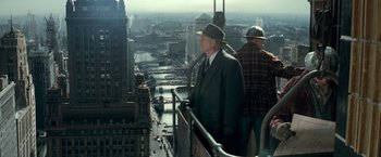 Movie still from “The Monuments Men” (2014), directed by George Clooney – A man in a suit and hat looks out over a city; Wide shot, High angle