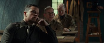 Movie still from “The Monuments Men” (2014), directed by George Clooney – A man sitting at a table in front of two other men; Medium shot, Over the shoulder angle