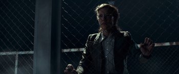 Movie still from “The Monuments Men” (2014), directed by George Clooney – A woman standing in front of a chain link fence at night; Medium shot, Low angle