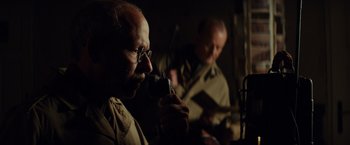 Movie still from “The Monuments Men” (2014), directed by George Clooney – A man with glasses is holding a microphone; Close Up shot, Low angle