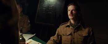 Movie still from “The Monuments Men” (2014), directed by George Clooney – A man in a military uniform sitting at a table; Medium shot, Low angle