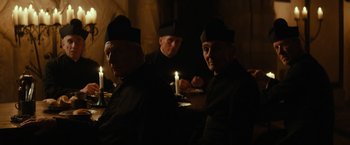 Movie still from “The Monuments Men” (2014), directed by George Clooney – A group of men sitting next to each other in a dark room; Medium shot, Over the shoulder angle