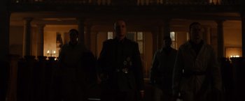 Movie still from “The Monuments Men” (2014), directed by George Clooney – A group of men standing in a dark room; Medium shot, Low angle