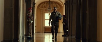 Movie still from “The Monuments Men” (2014), directed by George Clooney – A man walking down a hallway holding a helmet; Wide shot, Low angle