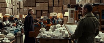 Movie still from “The Monuments Men” (2014), directed by George Clooney – A woman standing in front of a table filled with cups and saucers; Medium shot, High angle