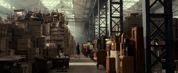 Movie still from “The Monuments Men” (2014), directed by George Clooney – A woman walking through a room filled with lots of wooden furniture; Extreme Wide shot, High angle