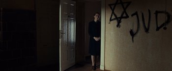 Movie still from “The Monuments Men” (2014), directed by George Clooney – A woman standing in front of an open door in a room; Wide shot, Low angle