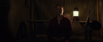 Movie still from “The Monuments Men” (2014), directed by George Clooney – A man sitting in the dark in a room; Medium shot, Low angle