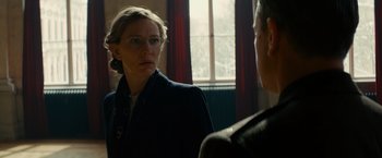 Movie still from “The Monuments Men” (2014), directed by George Clooney – A woman wearing glasses and a black jacket is talking to a man in front of a window; Close Up shot, Over the shoulder angle