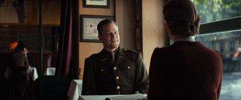 Movie still from “The Monuments Men” (2014), directed by George Clooney – A man in a military uniform sitting at a table; Medium shot, Over the shoulder angle