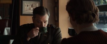 Movie still from “The Monuments Men” (2014), directed by George Clooney – A man drinking a cup of coffee in front of a mirror; Medium shot, Over the shoulder angle
