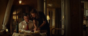 Movie still from “The Monuments Men” (2014), directed by George Clooney – A woman standing at a dinner table with a man; Medium shot, Low angle