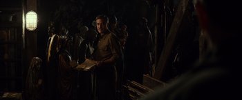 Movie still from “The Monuments Men” (2014), directed by George Clooney – A group of people standing around in a dark room; Medium shot, Over the shoulder angle