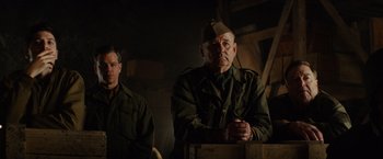 Movie still from “The Monuments Men” (2014), directed by George Clooney – A man in a military uniform sitting next to another man; Medium shot, Low angle