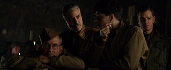 Movie still from “The Monuments Men” (2014), directed by George Clooney – A group of men standing next to each other in a room; Medium shot, Over the shoulder angle