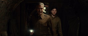 Movie still from “The Monuments Men” (2014), directed by George Clooney – A man and a man holding a flashlight in the dark; Medium shot, Low angle