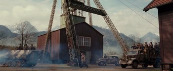 Movie still from “The Monuments Men” (2014), directed by George Clooney – A man and a woman walking under a large crane; Extreme Wide shot, Low angle