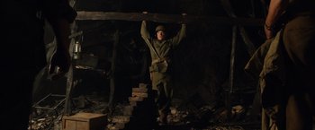 Movie still from “The Monuments Men” (2014), directed by George Clooney – A man holding a piece of wood over his head; Medium shot, Low angle