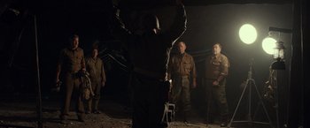 Movie still from “The Monuments Men” (2014), directed by George Clooney – A group of men standing in a dark room; Medium shot, Low angle