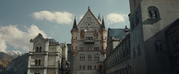 Movie still from “The Monuments Men” (2014), directed by George Clooney – A very tall castle like building with a clock on it's side; Extreme Wide shot, Low angle