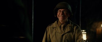Movie still from “The Monuments Men” (2014), directed by George Clooney – An older man wearing a hat and glasses and smiling; Close Up shot, Over the shoulder angle