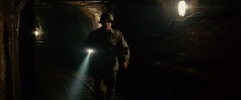 Movie still from “The Monuments Men” (2014), directed by George Clooney – A man wearing a helmet and holding a flashlight in the dark; Medium shot, High angle