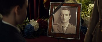 Movie still from “The Monuments Men” (2014), directed by George Clooney – An old photo of a man in uniform with a bouquet of flowers in front of him; Extreme Close Up shot, Low angle