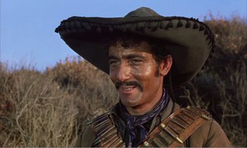 Movie still from “Django” (1966), directed by Sergio Corbucci – A man in a cowboy hat smiles for the camera; Close Up shot, Low angle