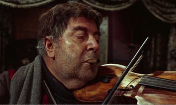 Movie still from “Django” (1966), directed by Sergio Corbucci – A person with a violin; Close Up shot, Low angle