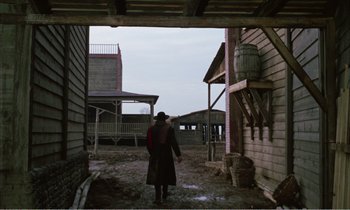 Movie still from “Django” (1966), directed by Sergio Corbucci – A man standing in the dirt in front of a building; Wide shot, Low angle