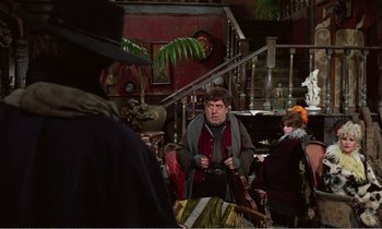 Movie still from “Django” (1966), directed by Sergio Corbucci – A man holding a camera in a room with people; Wide shot, Over the shoulder angle